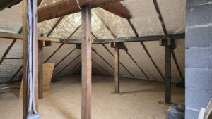 Izolacja poddasza przed ociepleniem pianą PUR, ukazująca widok na drewnianą konstrukcję dachu i przygotowane miejsce do instalacji. Idealne dla osób poszukujących efektywnych metod ocieplania domu i fundamentów.