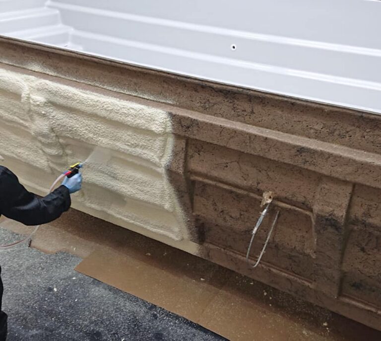 Izolacja poddasza z użyciem piany PUR, pokazująca aplikację materiału w celu ocieplenia domu. Osoba nakłada piana PUR na ścianę fundamentu, zapewniając skuteczną izolację termiczną. Ocieplanie fundamentów przy użyciu nowoczesnej technologii.