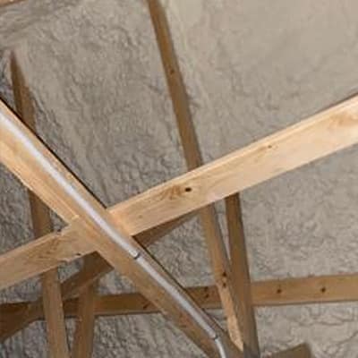 Izolacja poddasza wykonana pianką PUR, ukazująca drewniane konstrukcje oraz efekt ocieplenia, idealna dla poprawy efektywności energetycznej domu.